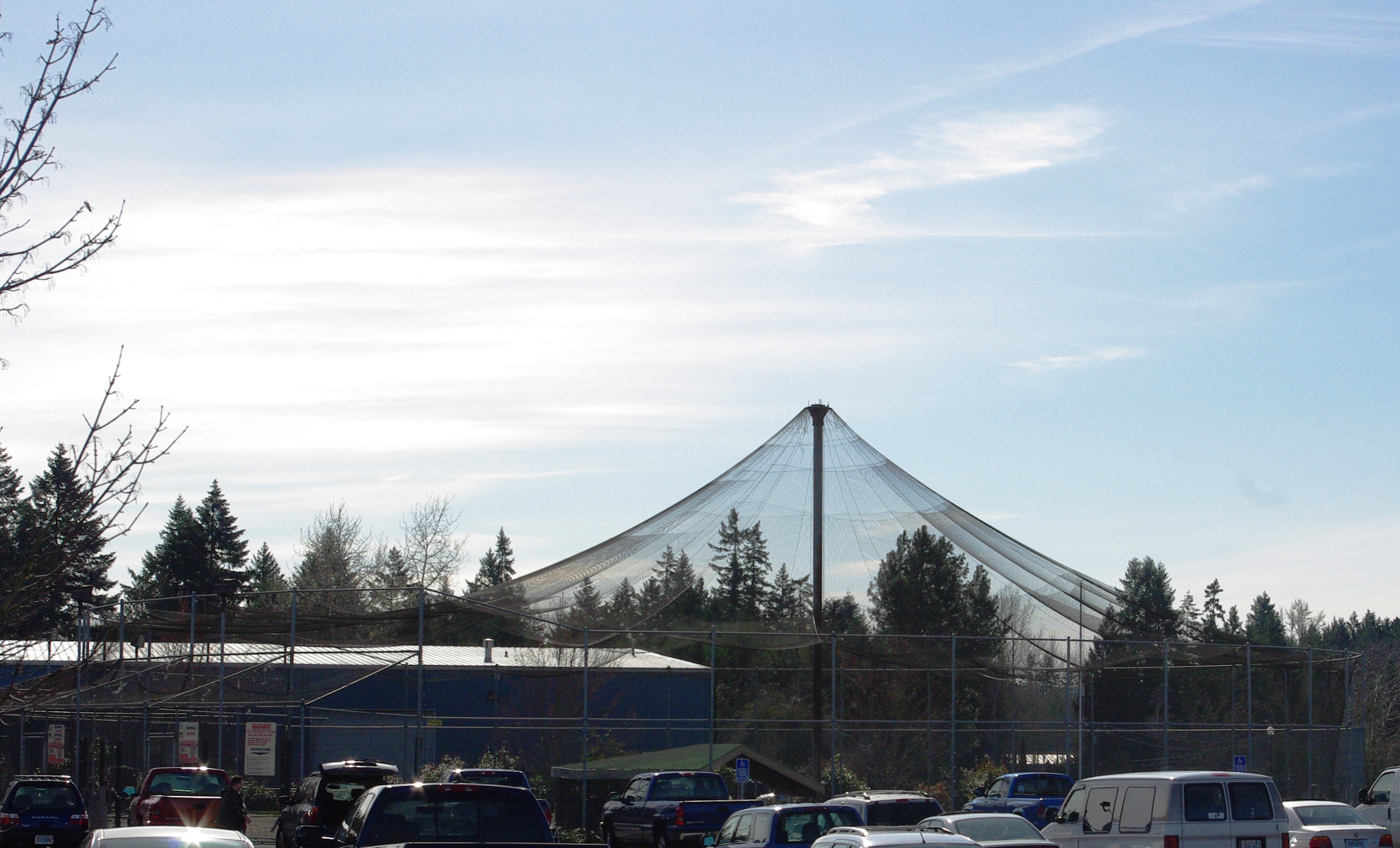 An outdoor batting cage enclosed by fencing and netting